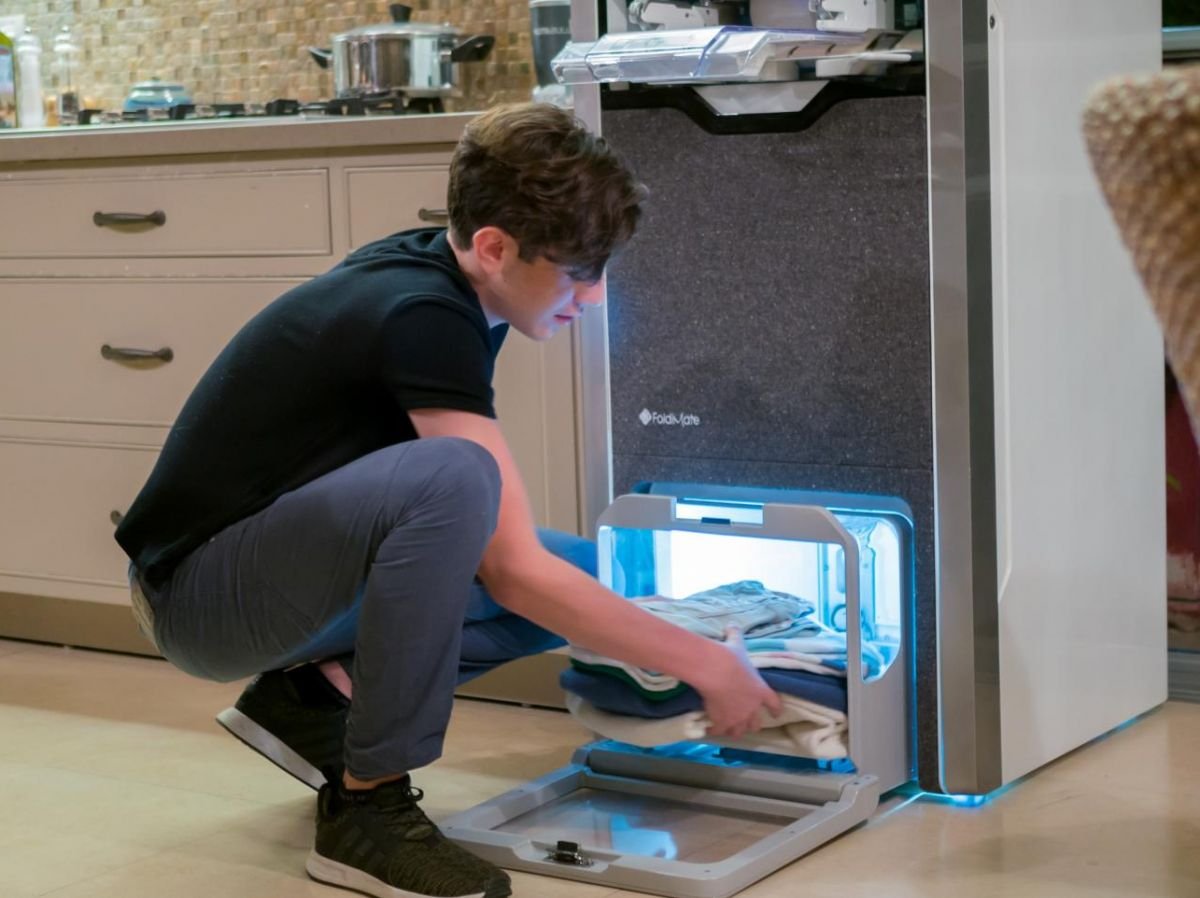 A young boy removes his impeccably folded and ironed clothes from the FoldiMate machine, offering fast, quality results. Find out how this innovative solution simplifies folding and ironing on el.foldimateofficial.com.